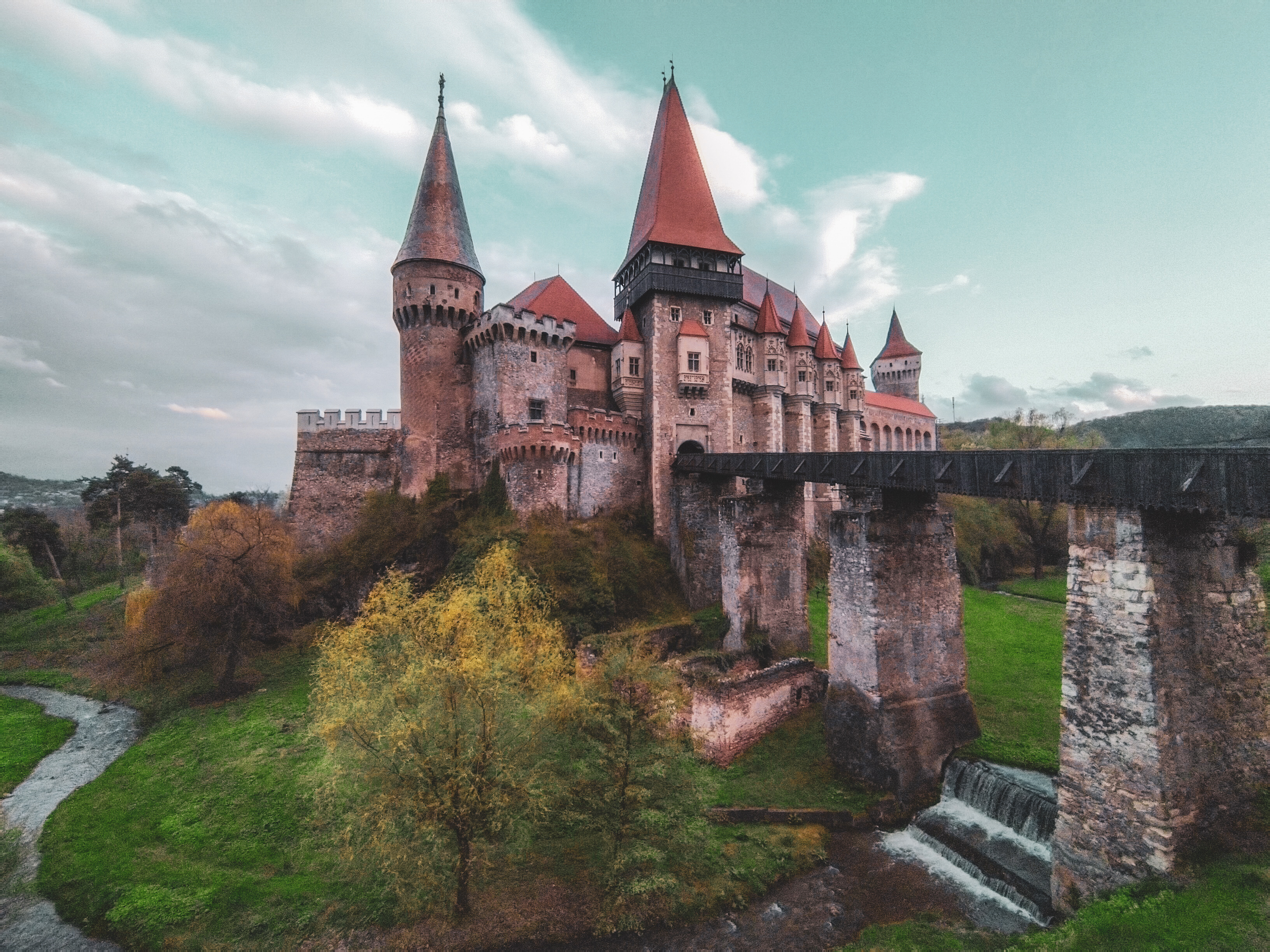 Hrad Hunedoara – pohled na tento impozantní středověký hrad zepředu, s viditelným mostem, který vede do pevnosti.